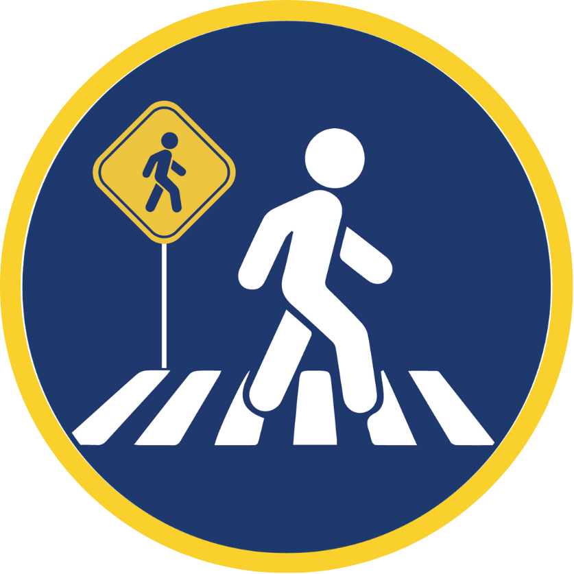 A pedestrian crossing a marked crosswalk with pedestrian warning sign